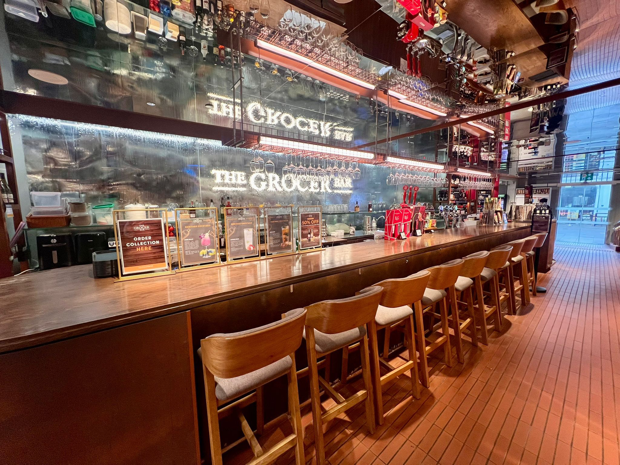 Long wooden counter with barstools at The Grocer Bar in FairPrice Finest Clarke Quay.